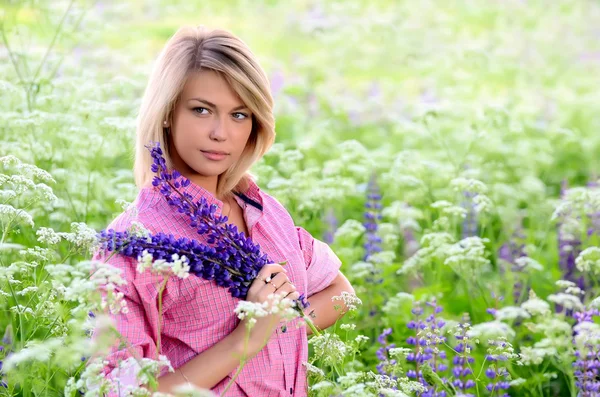 Donna in campo con fiori di lupino — Foto Stock