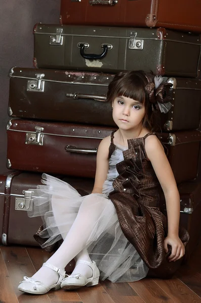 Girl sitting on retro suitcases — Stock Photo, Image