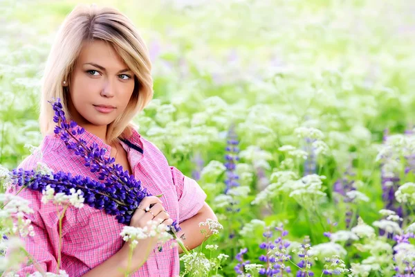 Mulher no campo com flores lupin — Fotografia de Stock