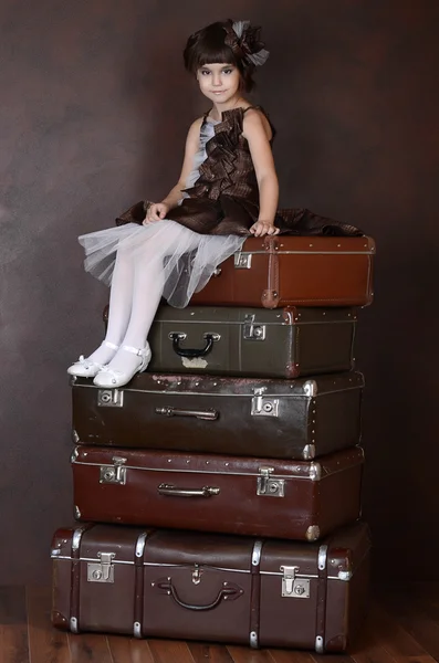 Girl sitting on retro suitcases — Stock Photo, Image