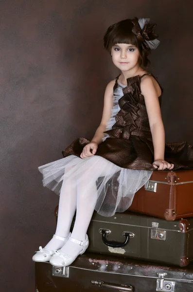 Девушка сидит на ретро чемоданах — стоковое фото
