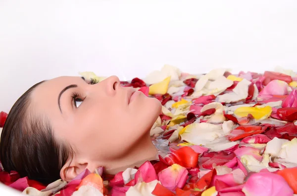 Frau im Bad mit Rosenblättern — Stockfoto