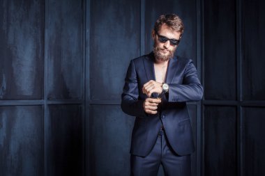 Duvara karşı gri elbiseli acımasız sakallı adam