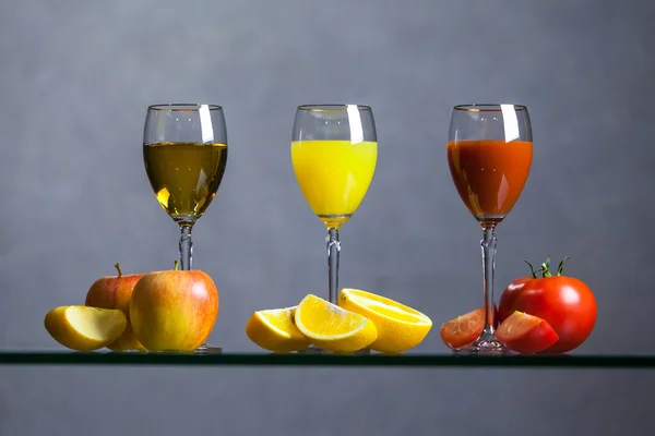 Різні соки і фрукти на скляному столі — стокове фото