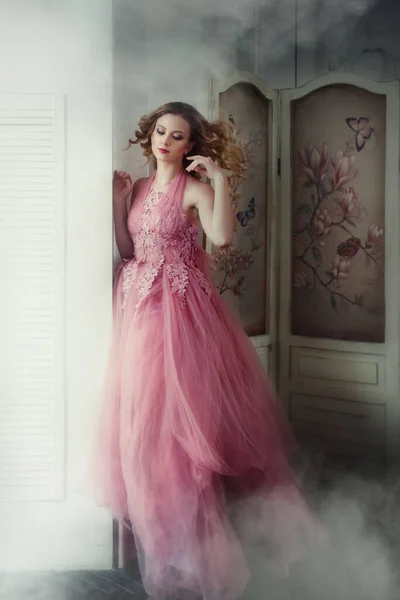 一个浪漫的仙女 一头蓬松的头发 穿着粉红的老式衣服 在雾中摆姿势 — 图库照片