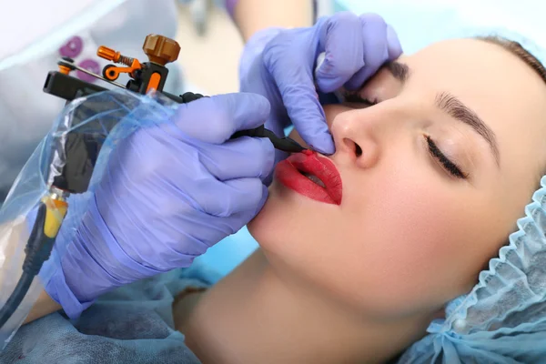 Cosmetologist making permanent makeup on woman's face — Stock Photo, Image