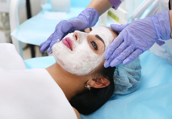 Doctor beautician applies a clay mask on face hands beautiful wo — Stock Photo, Image