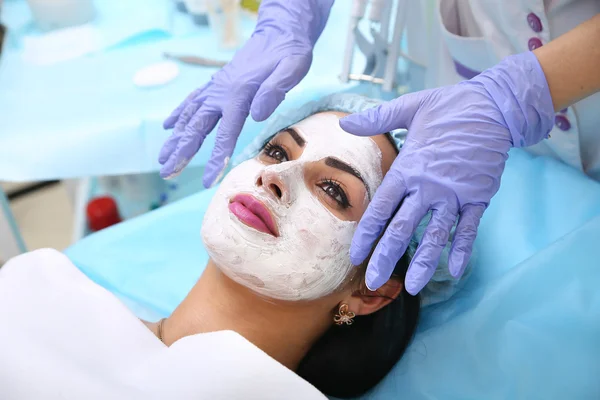 Médico esteticista aplica una máscara de arcilla en la cara manos hermosa wo — Foto de Stock