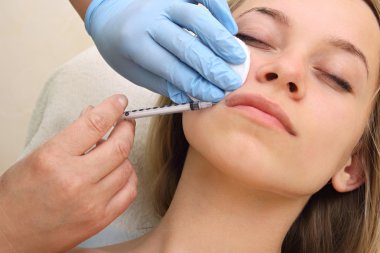 Güzel kadın bir enjeksiyon dudaklarını içinde alır..