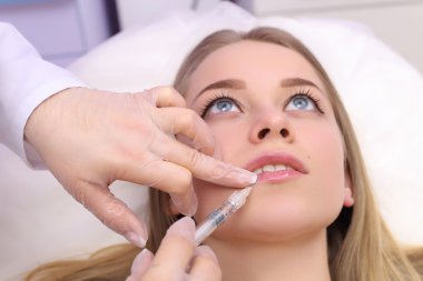 Güzel kadın bir enjeksiyon dudaklarını içinde alır..