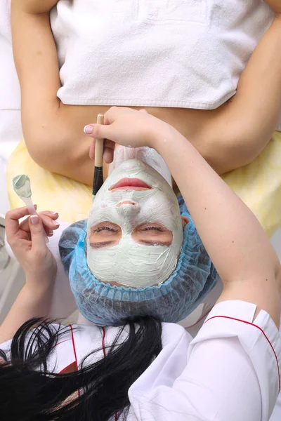 Mujer con máscara facial de arcilla en spa de belleza . — Foto de Stock