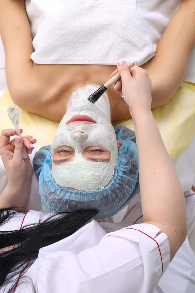 Mujer con máscara facial de arcilla en spa de belleza . — Foto de Stock