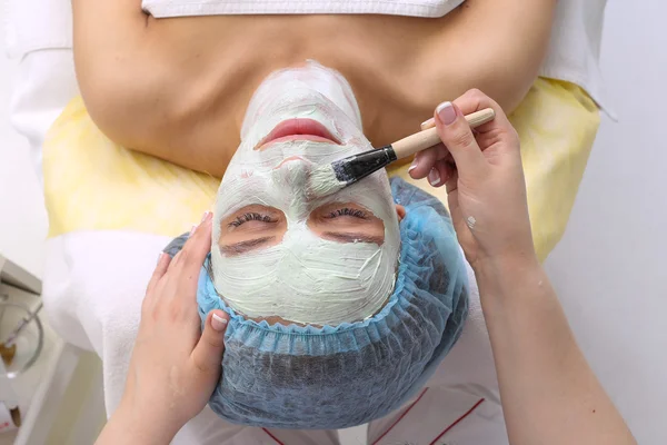 Kvinna med lera ansiktsmask i beauty spa. — Stockfoto