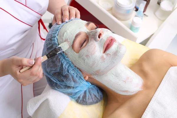 Donna con maschera viso in argilla in beauty spa . — Foto Stock