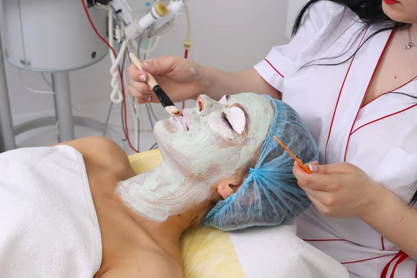 Donna con maschera viso in argilla in beauty spa . — Foto Stock