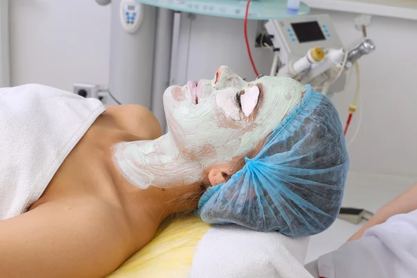 Mujer con máscara facial de arcilla en spa de belleza . — Foto de Stock