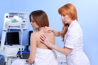 Doktor kadın hastanın cilt inceliyor