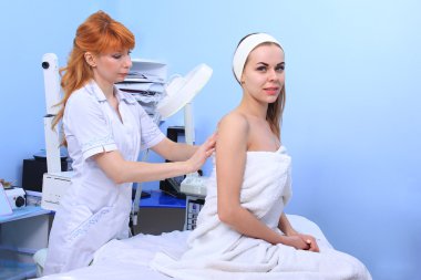 Doktor kadın hastanın cilt inceliyor