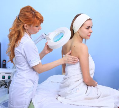 Doktor kadın hastanın cilt inceliyor