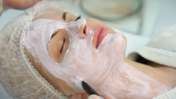 Le mani di cosmetologo applicano la crema a mezza faccia — Video Stock