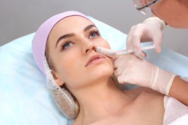 Güzel kadın bir enjeksiyon dudaklarını içinde alır..