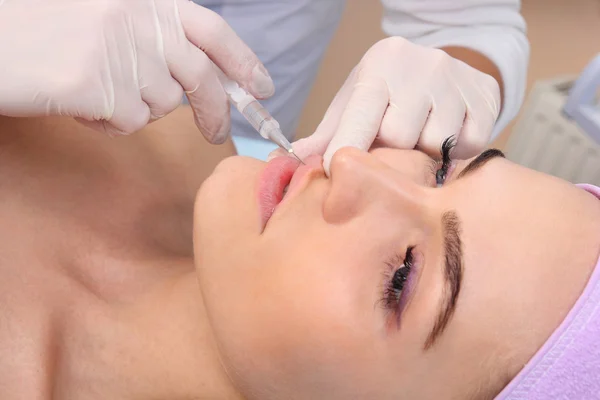 Beautiful woman gets an injection in her lips. — Stock Photo, Image