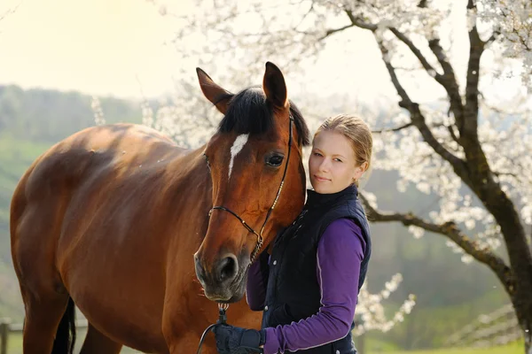 Beautiful girl with bay horse in spring garden — Stock Photo, Image