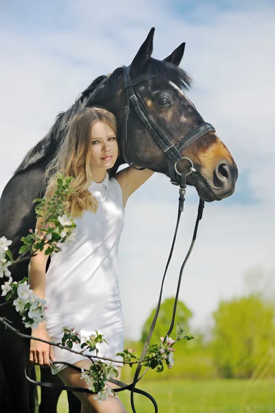 Mooi meisje en paard in bloei lente tuin — Stockfoto