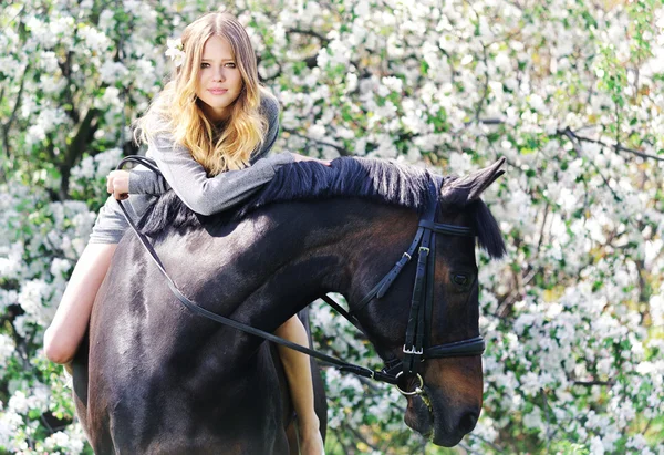 Mooi meisje en paard in bloei lente tuin — Stockfoto