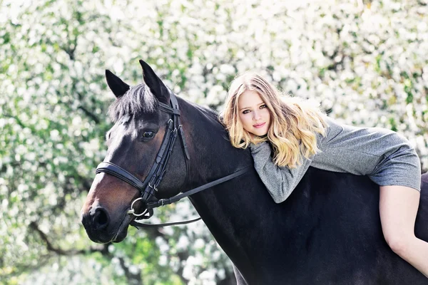 Mooi meisje en paard in bloei lente tuin — Stockfoto