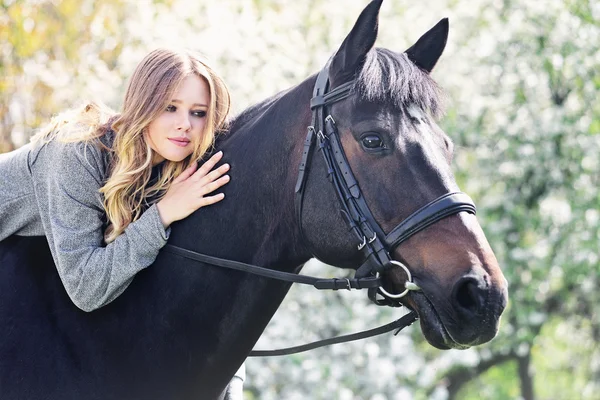 Vacker flicka och häst i blommande våren trädgård — Stockfoto