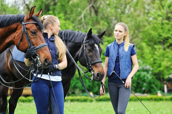 Två unga flickor - dressyrryttare med hästar — Stockfoto