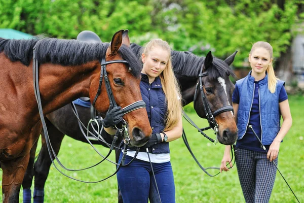 Två unga flickor - dressyrryttare med hästar — Stockfoto