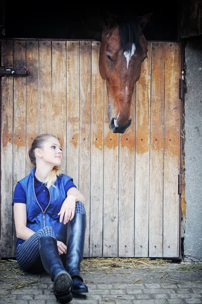 Jezdecké dívka a kůň ve stáji — Stock fotografie