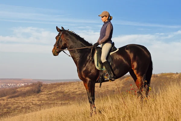 Ung kvinna som rider en häst i höst arkiverat — Stockfoto