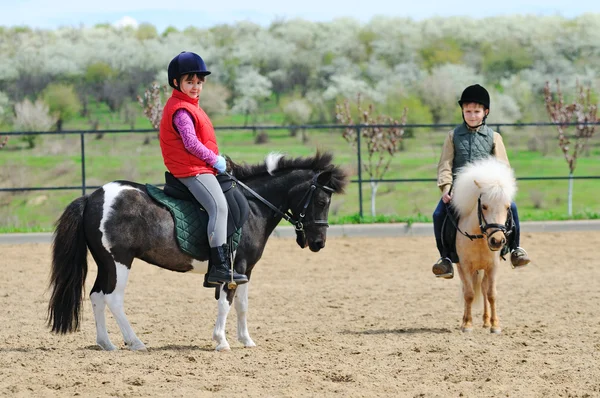 Pojke och flicka rida en ponny — Stockfoto