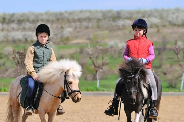 Ragazzo e ragazza cavalcando un pony — Foto Stock