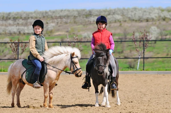 Ragazzo e ragazza cavalcando un pony — Foto Stock