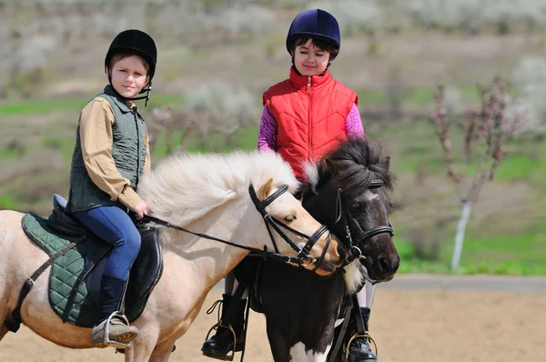 Ragazzo e ragazza cavalcando un pony — Foto Stock