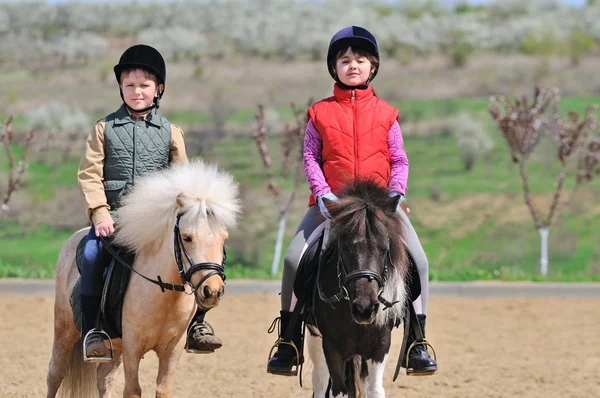 Jongen en meisje rijden op een pony — Stockfoto