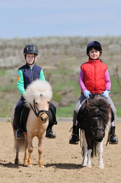 Ragazzo e ragazza cavalcando un pony — Foto Stock