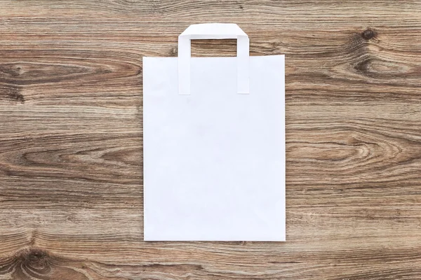 Білий паперовий сумка на дерев'яному фоні . — стокове фото