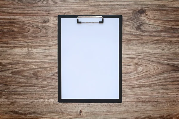 Blanco papier in Klembord op houten tafel — Stockfoto