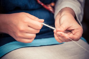 Geleneksel yün örme gösterisi yapan bir kadının elleri.