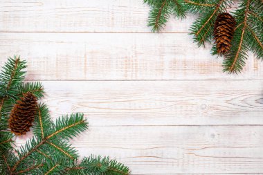 Noel arkaplanı - beyaz ahşap bir masanın üzerinde külahlı köknar dalları. Düz düzen, kopyalama alanı ile üst görünüm bileşimi sınırı.