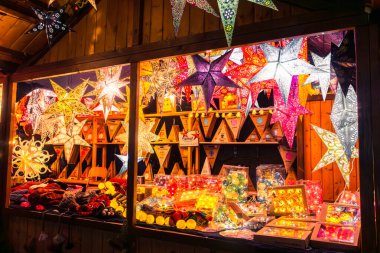 Mannheim, Almanya - 23 Aralık 2022: Ilık turuncu, sarı ve kırmızı tonlarda parlayan parlak, karmaşık dizayn edilmiş yıldız fenerleri, mevsimlik dekor ile bir Noel pazarını süslüyor..