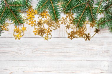 Noel arkaplanı - hafif ahşap bir yüzeyde yeşil köknar dallarına sarılı altın kar tanesi çelenkleri. Düz düzen, kopyalama alanı ile üst görünüm bileşimi sınırı.