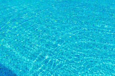 Güneş ışığını yansıtan bir havuzda berrak mavi su yüzeyi karmaşık dalgalanma desenleri oluşturur. Rahatlama, sükunet ve yaz havası. Tazelik ve rahatlık hissi uyandırıyor..