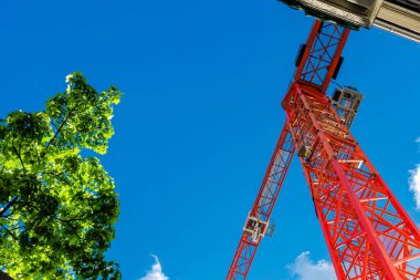 Düşük açı açısı parlak kırmızı bir vinç yapısına bakıyor ve açık mavi gökyüzüne karşı duruyor.