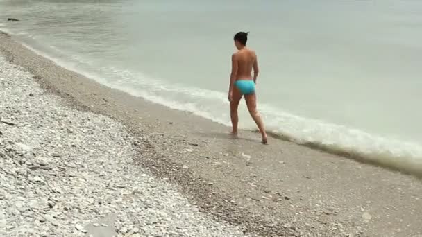 Naken ung kvinna promenerar på stranden kusten — Stockvideo